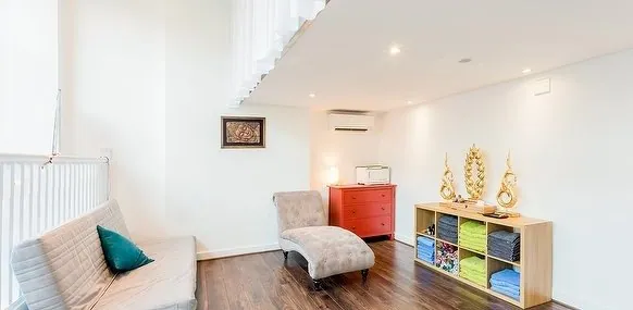 Waiting area with a sofa and treatment-room entrance at Bodyness in Battersea.