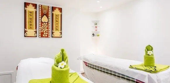 Bodyness treatment room with a white treatment bed and green towels.