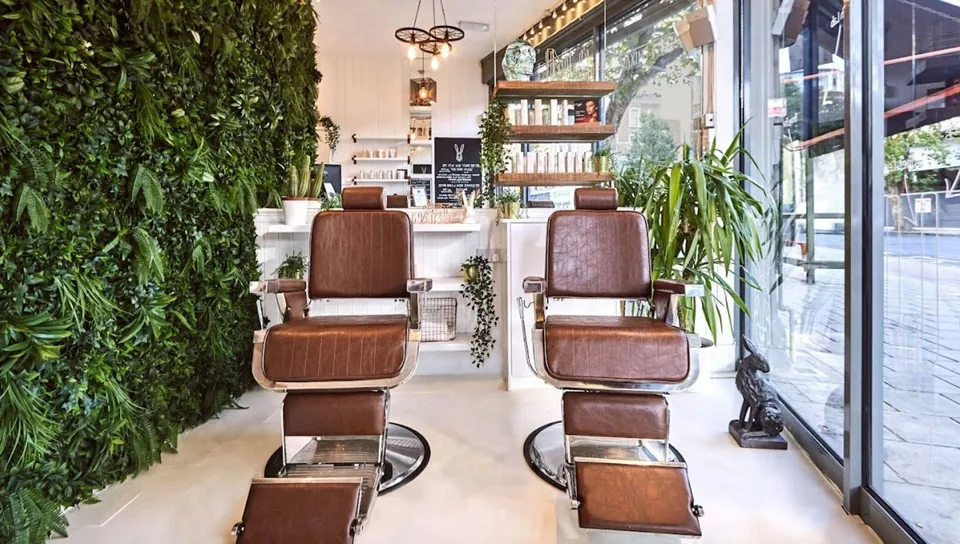 Naked Hare salon chairs beside a planted wall and the front window.