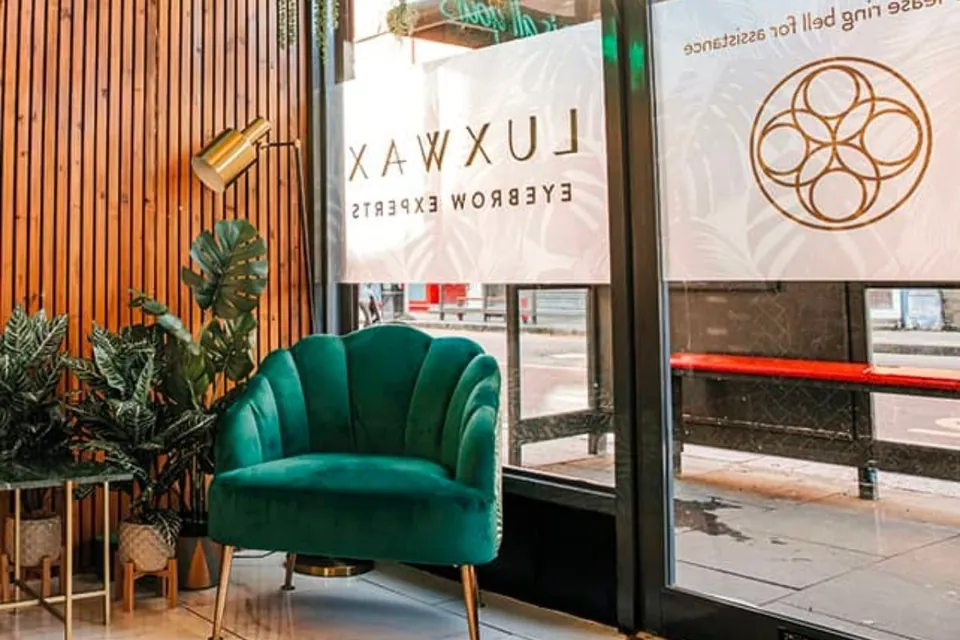 Green reception chair and wood-panelled entrance area at LuxWax Crouch End.