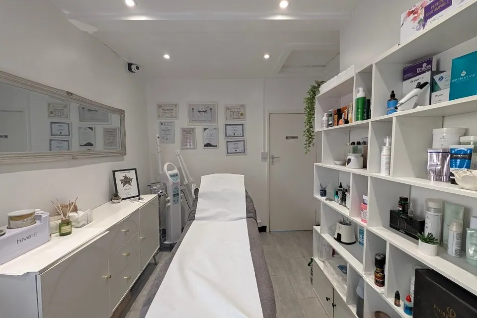 Beauty by Daniela treatment room with a white couch, mirrors and product shelving.
