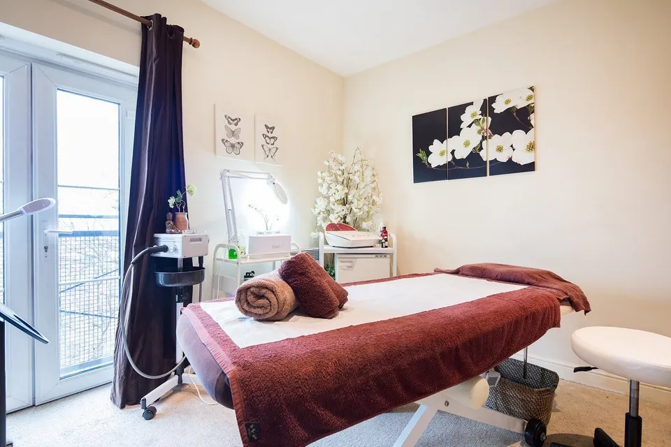 Beauty Place treatment room with a burgundy-covered couch and a window beside the treatment area.