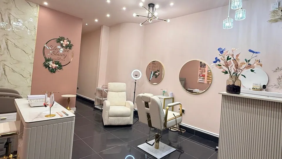 Elegance Beauty interior with pale pink walls, round mirrors and cream salon chairs.