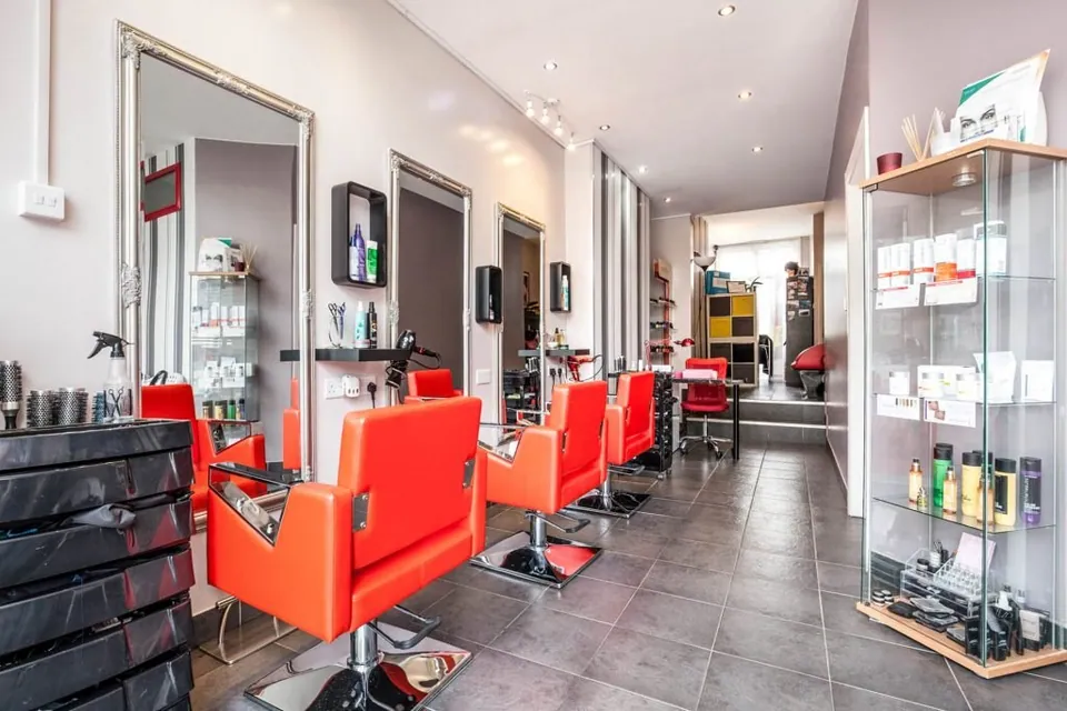 Free Style salon interior with red styling chairs, wall mirrors and product cabinets.