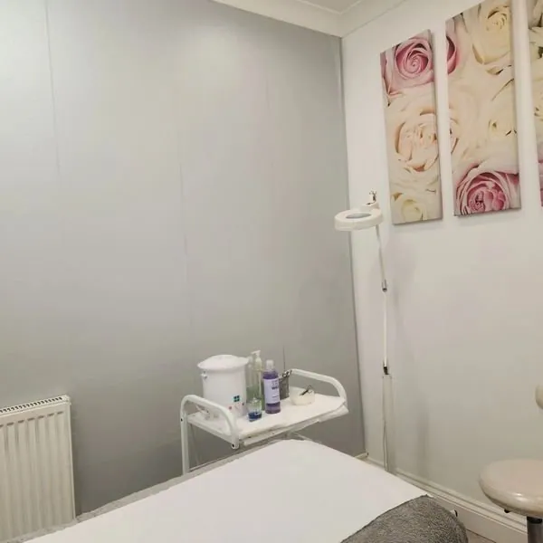 Ageless Beauty treatment room with a white couch, supply trolley and floral wall art.