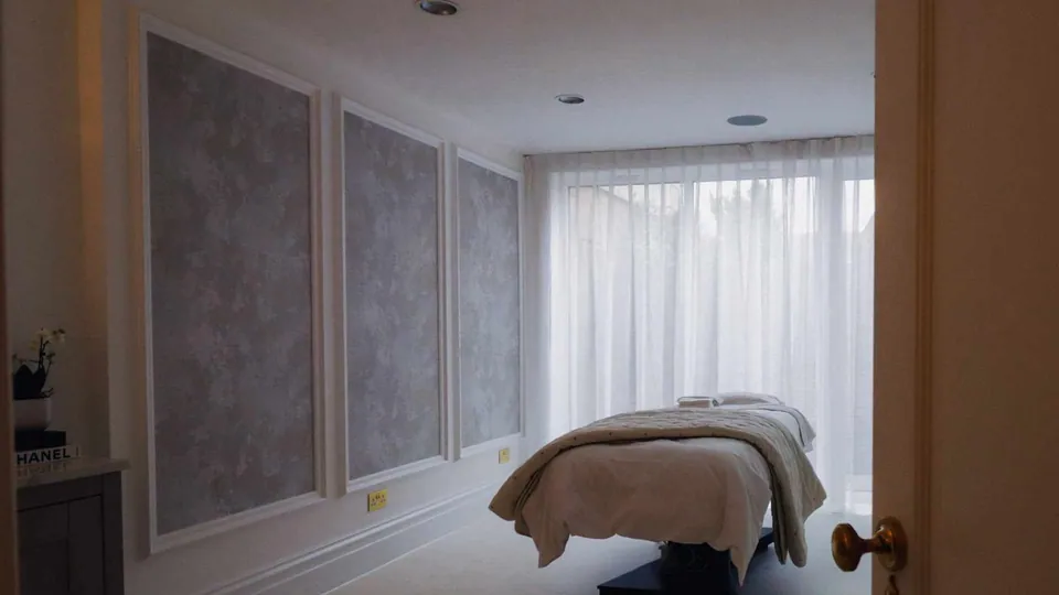 Treatment couch in a curtained treatment room at Luminis Chislehurst.