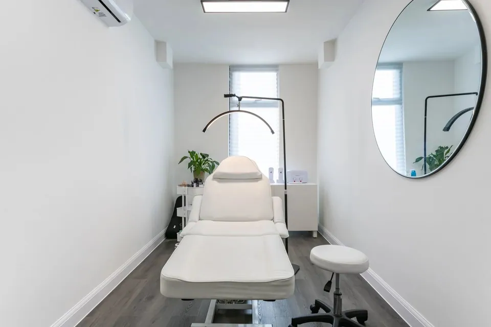 NABA Studios treatment room with a white couch and round wall mirror.