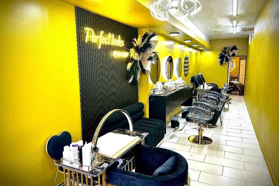 Yellow-walled Perfect Looks Beauty Studio with styling chairs, mirrors and its wall sign.