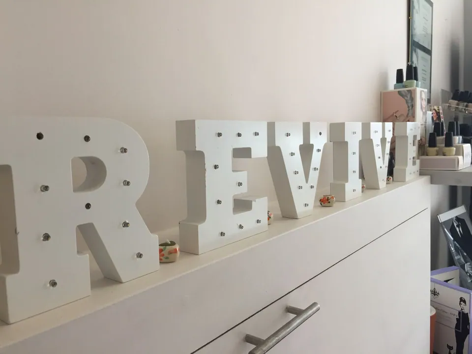 Illuminated REVIVE letters on a cabinet in the Surbiton salon reception